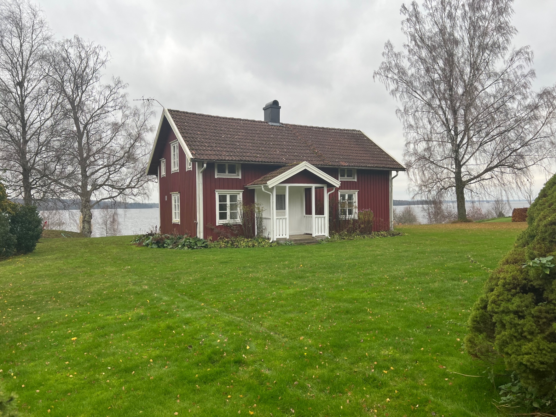 Röd stuga vid sjön i Klastorp