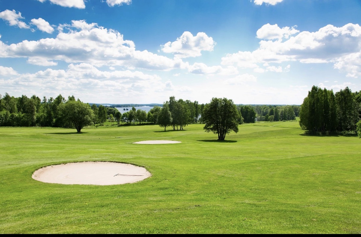 Värnamo Golfklubbs gröna fairways med bunkrar och sjön Hindsen i bakgrunden